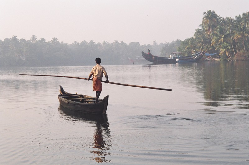 A man punting a canoe along the backwaters